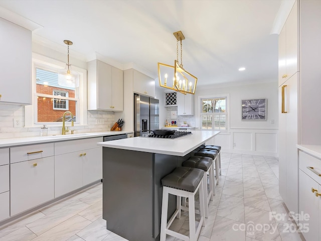 kitchen with a kitchen bar, sink, ornamental molding, a kitchen island, and stainless steel appliances