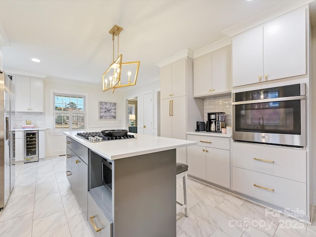 kitchen with a kitchen island, appliances with stainless steel finishes, white cabinets, wine cooler, and hanging light fixtures