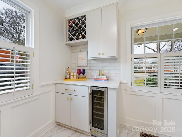 bar with tasteful backsplash, white cabinetry, and wine cooler