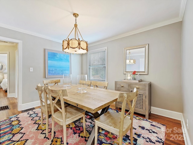 dining space with ornamental molding, a chandelier, and light hardwood / wood-style flooring