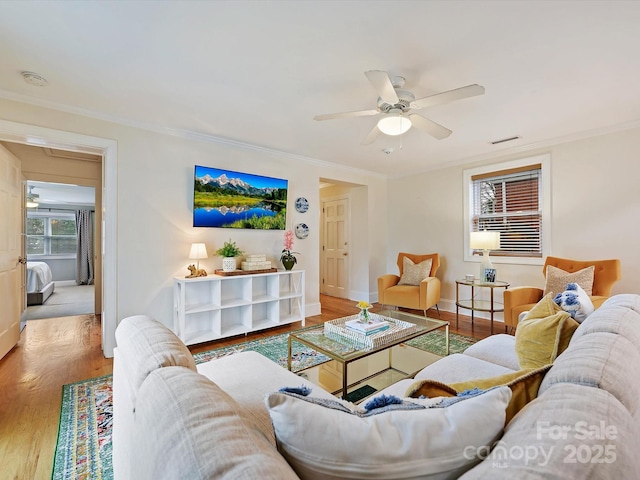 living room featuring hardwood / wood-style floors, ornamental molding, and ceiling fan