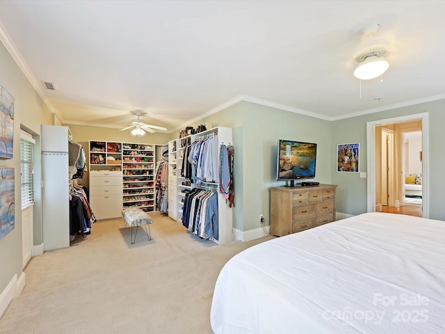 carpeted bedroom with crown molding, ceiling fan, and a spacious closet