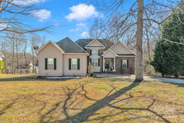 view of front of home featuring roof with shingles, a front lawn, and brick siding