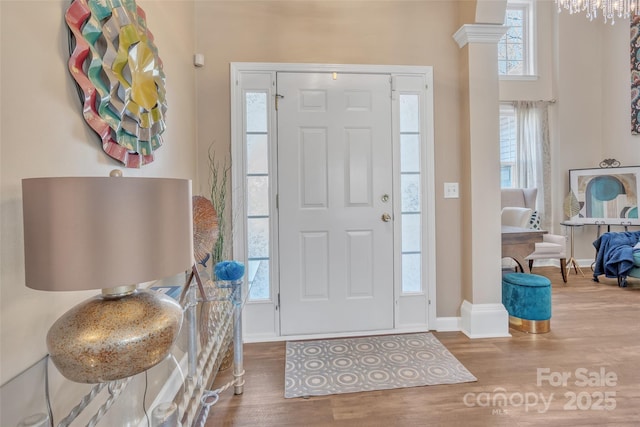 foyer entrance with plenty of natural light, decorative columns, baseboards, and wood finished floors