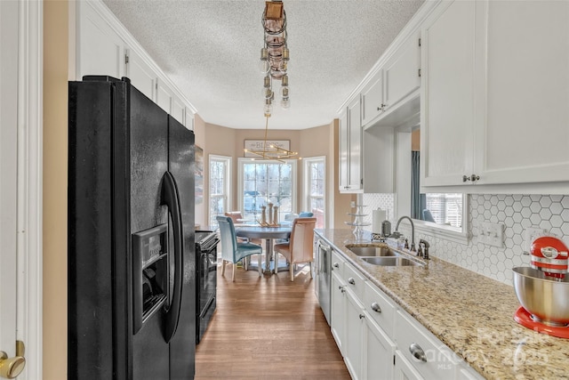 kitchen featuring light stone counters, pendant lighting, white cabinetry, and black appliances