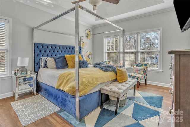 bedroom with baseboards, ceiling fan, wood finished floors, a textured ceiling, and crown molding