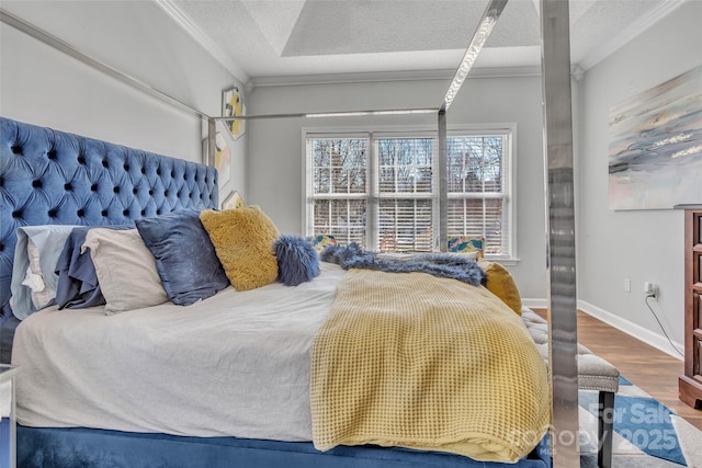 bedroom featuring crown molding, a textured ceiling, baseboards, and wood finished floors