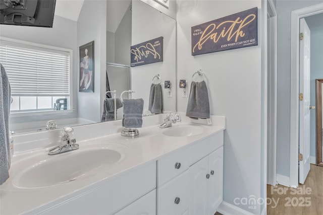 full bath with double vanity, baseboards, and a sink