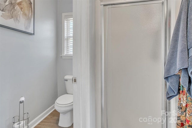 bathroom with toilet, baseboards, and wood finished floors