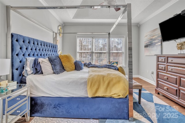 bedroom featuring a textured ceiling, ornamental molding, wood finished floors, and baseboards