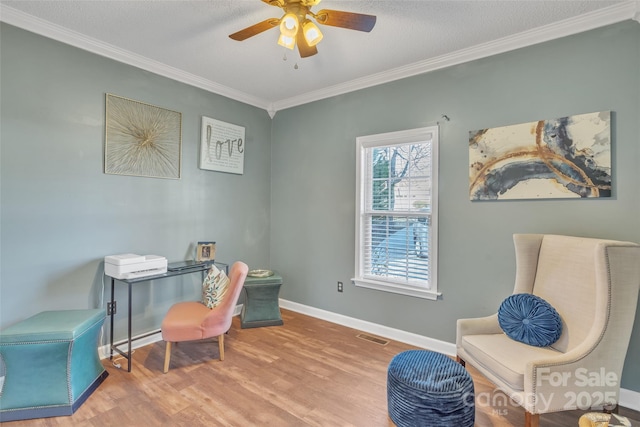 office area featuring ceiling fan, wood finished floors, visible vents, baseboards, and ornamental molding