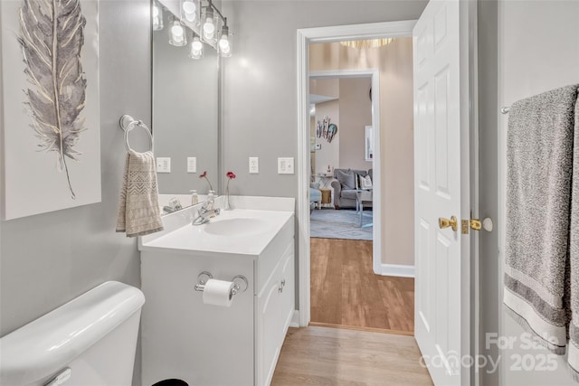 half bathroom featuring toilet, wood finished floors, and vanity