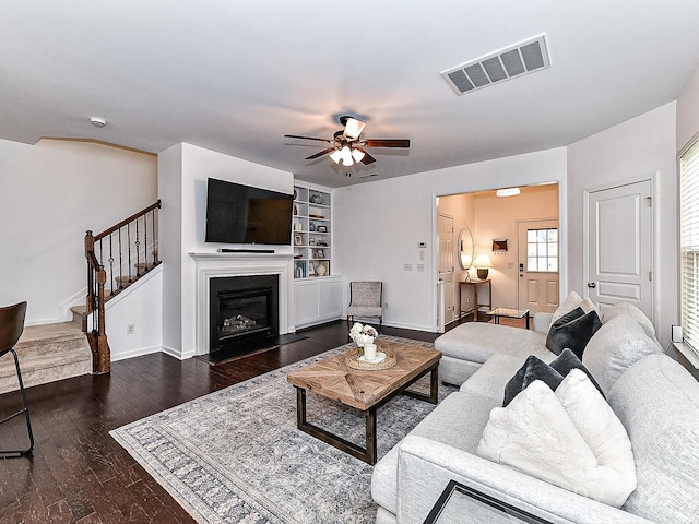 living room with dark wood-type flooring and ceiling fan