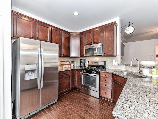 kitchen featuring tasteful backsplash, light stone countertops, appliances with stainless steel finishes, and sink