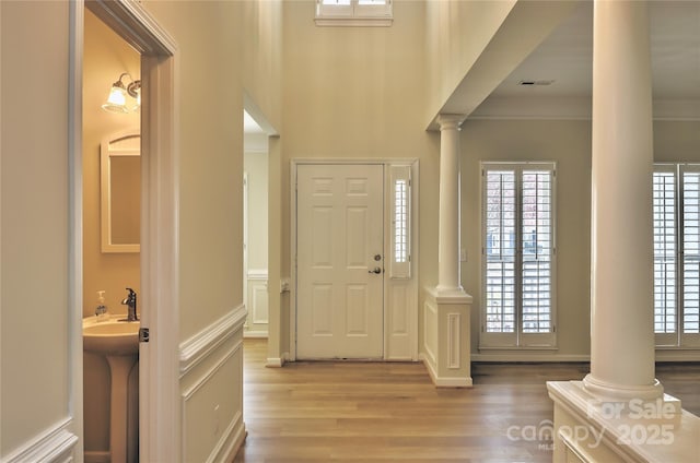 entryway with plenty of natural light, ornate columns, and wood finished floors