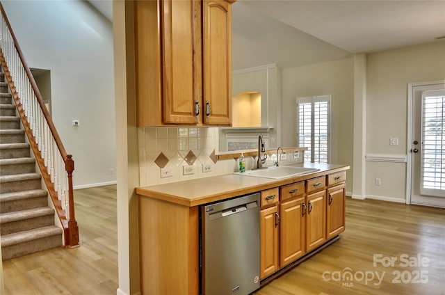 kitchen featuring a sink, light wood-type flooring, tasteful backsplash, and dishwasher