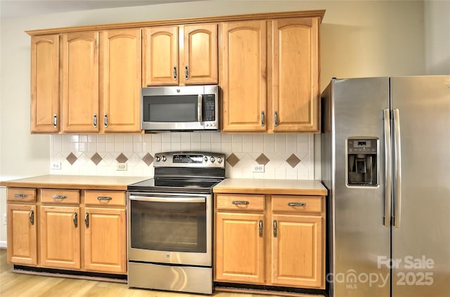 kitchen with backsplash, light wood-style floors, stainless steel appliances, and light countertops