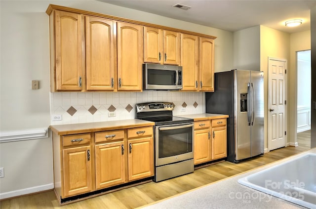 kitchen featuring light countertops, appliances with stainless steel finishes, light wood-style flooring, and visible vents