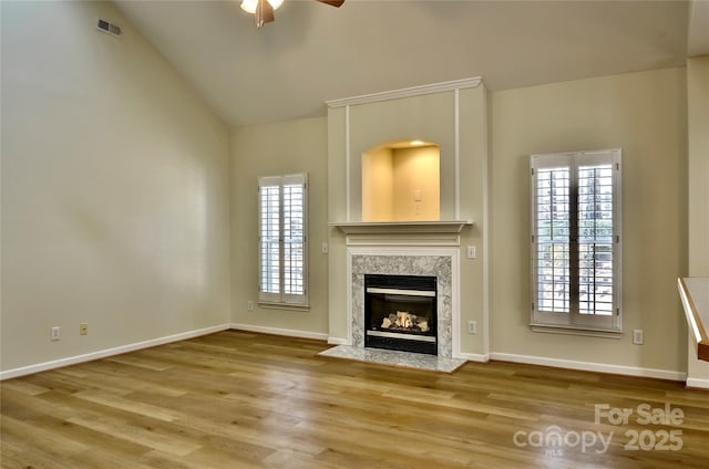 unfurnished living room featuring baseboards, visible vents, wood finished floors, and a high end fireplace