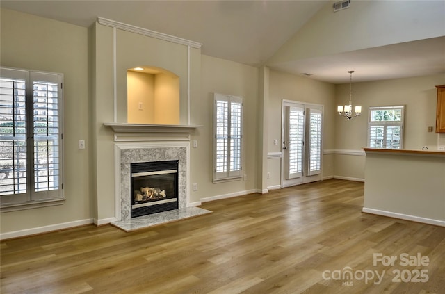 unfurnished living room with light wood-style floors, a wealth of natural light, visible vents, and a premium fireplace