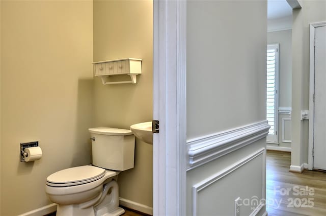 bathroom with ornamental molding, baseboards, toilet, and wood finished floors