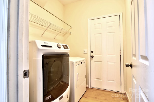 washroom featuring laundry area, washer and clothes dryer, and light wood finished floors