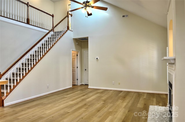 unfurnished living room with ceiling fan, a fireplace, baseboards, and wood finished floors