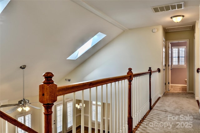 hallway with baseboards, visible vents, vaulted ceiling, and carpet flooring