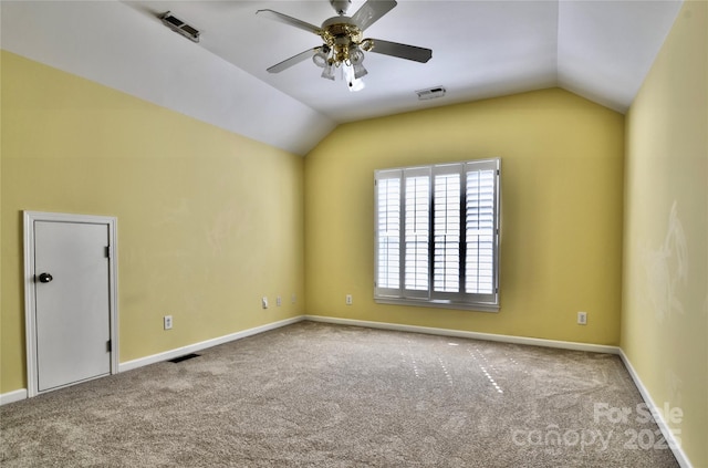 spare room featuring lofted ceiling, carpet, and visible vents