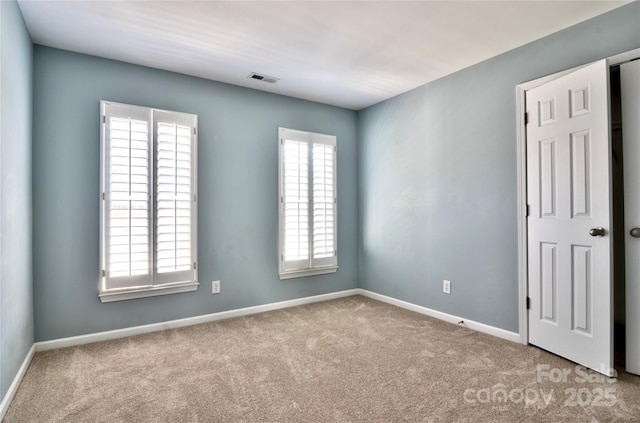 carpeted empty room with visible vents and baseboards