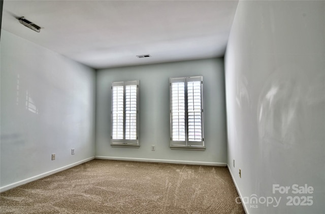 carpeted spare room featuring visible vents and baseboards