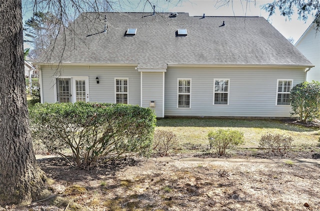 back of property featuring roof with shingles and a lawn