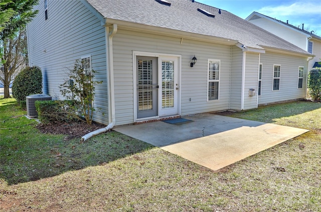 back of house with a shingled roof, cooling unit, a patio area, and a lawn