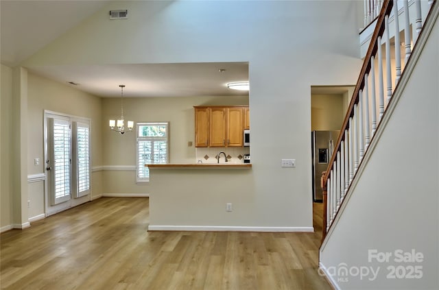 kitchen with visible vents, baseboards, an inviting chandelier, light wood-style floors, and refrigerator with ice dispenser