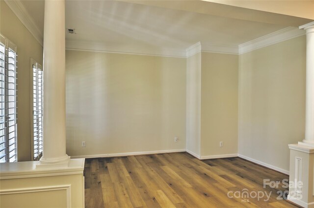 unfurnished room with baseboards, crown molding, ornate columns, and wood finished floors