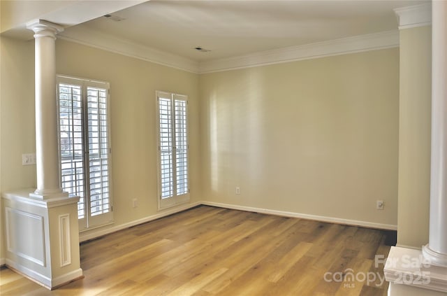 empty room with ornamental molding, ornate columns, and wood finished floors