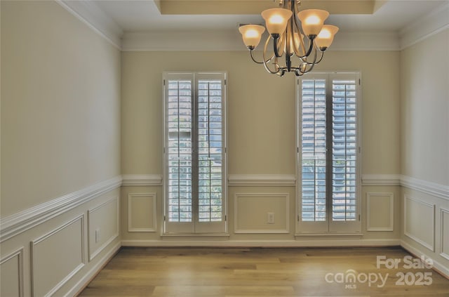 doorway featuring crown molding, a healthy amount of sunlight, a notable chandelier, and wood finished floors