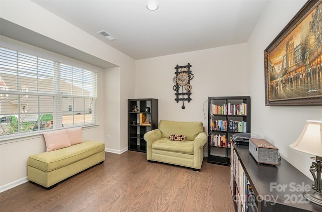 living area featuring baseboards, visible vents, and wood finished floors