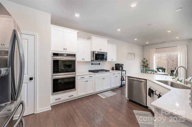 kitchen featuring dark wood-style flooring, a sink, white cabinets, light countertops, and appliances with stainless steel finishes