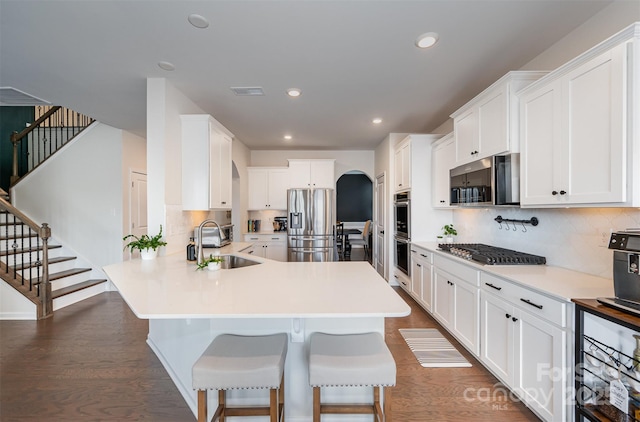 kitchen featuring light countertops, appliances with stainless steel finishes, a sink, and white cabinets