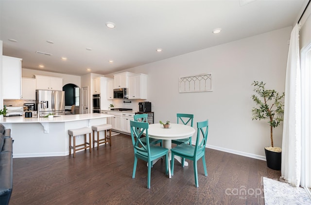 dining room featuring arched walkways, dark wood finished floors, recessed lighting, visible vents, and baseboards