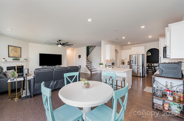 dining space with dark wood-style floors, arched walkways, ceiling fan, and recessed lighting