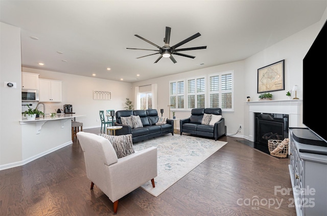 living room with baseboards, a glass covered fireplace, dark wood finished floors, and recessed lighting