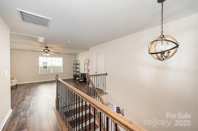 corridor with dark wood-style floors, baseboards, visible vents, and an upstairs landing