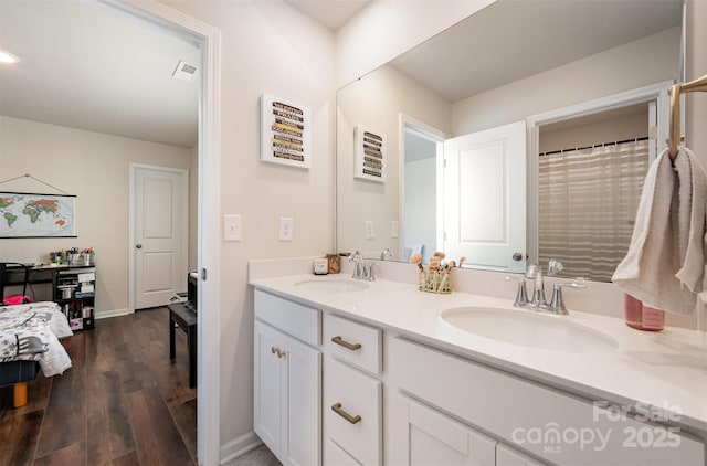 full bathroom featuring wood finished floors, a sink, baseboards, and double vanity