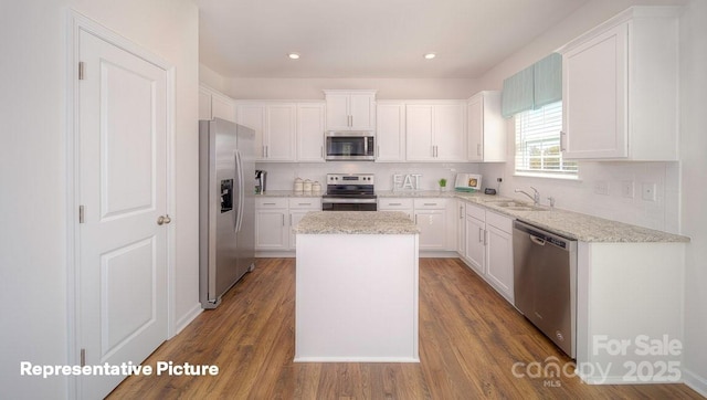 kitchen with sink, appliances with stainless steel finishes, white cabinetry, tasteful backsplash, and a kitchen island