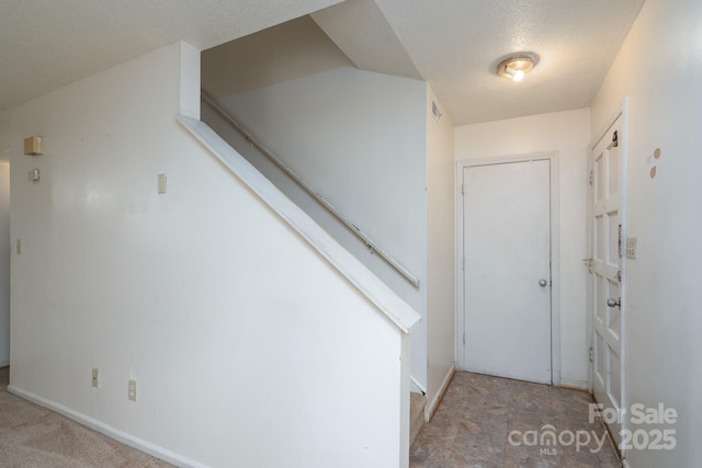 interior space with stairway, baseboards, a textured ceiling, and visible vents