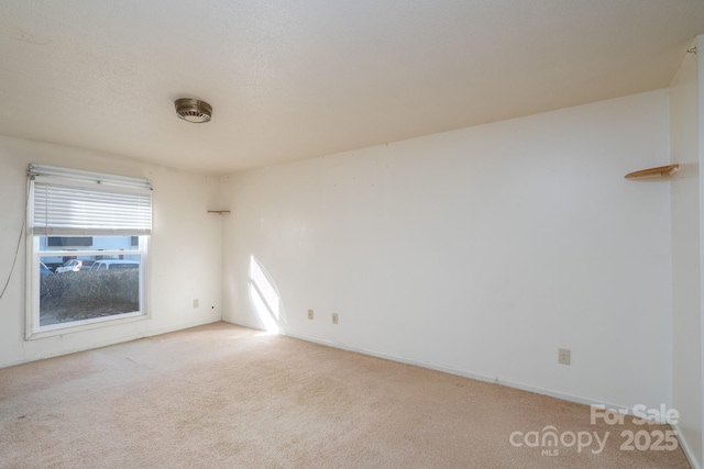 unfurnished room with light colored carpet and a textured ceiling