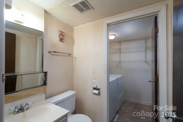 bathroom with wallpapered walls, independent washer and dryer, a spacious closet, vanity, and visible vents