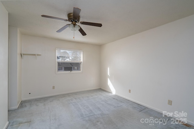 empty room with ceiling fan, light carpet, a textured ceiling, and baseboards